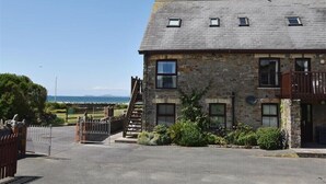 A stone building with a balcony, a staircase, and a view of the sea. - 5 The Coach House (Haverfordwest)