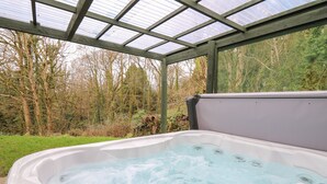 A hot tub with a control panel, surrounded by a wooden pergola and a natural landscape. - Trawsnant Cottage (Llandysul)