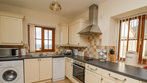 A kitchen with a washing machine, oven, and a large window with a view. - Beudy (Cardigan)