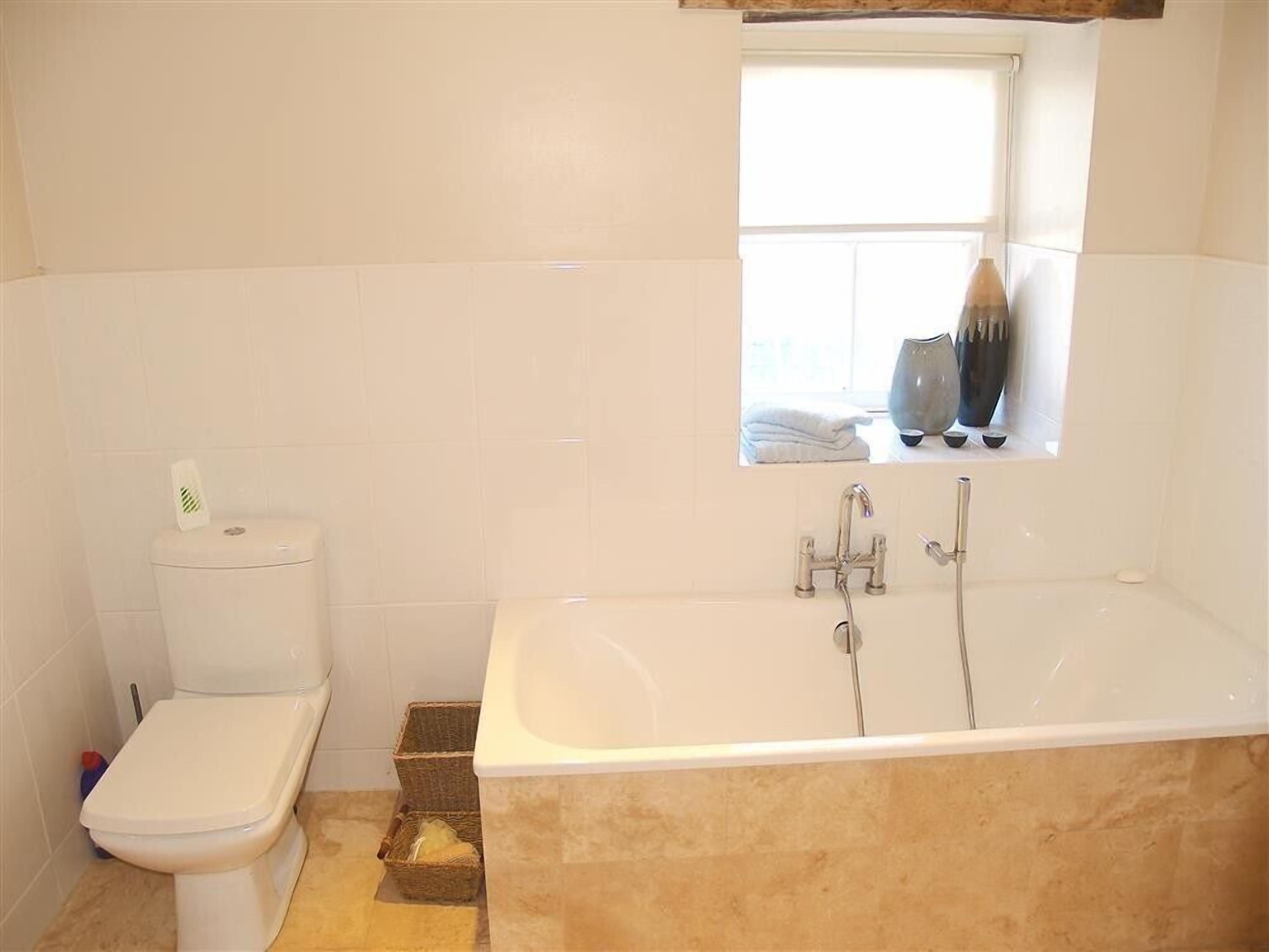 Un baño con inodoro, bañera y ventana.