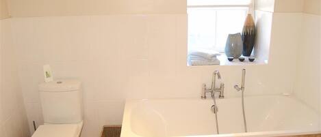 Un baño con inodoro, bañera y ventana.