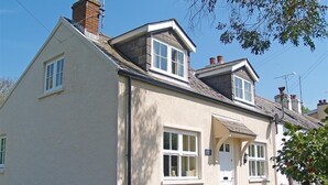 Ein zweistöckiges Haus mit weißer Fassade, einer Veranda und einem Schornstein.