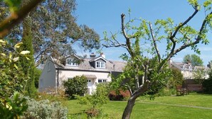 Ein Haus mit Garten, Rasen und einem Baum im Vordergrund.