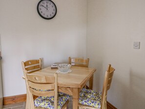 A dining table with four wooden chairs, a glass bowl, and a wall clock. - Llaethdy (Cardigan)