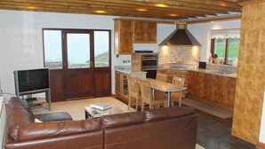 Una sala de estar con un sofá de cuero marrón, un televisor y un comedor con mesa y sillas.