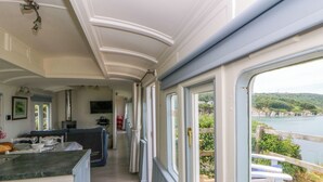 Bootinterieur met een keukenhoek, zitplaatsen en uitzicht op zee.