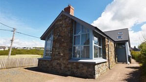 A stone house with large windows and a small attached garage. - Seabrook (Haverfordwest)