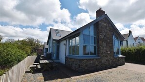 A stone house with a large window and a wooden deck. - Seabrook (Haverfordwest)