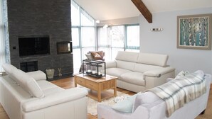 A spacious living room with a fireplace, white sofas, and a wooden coffee table. - Seabrook (Haverfordwest)