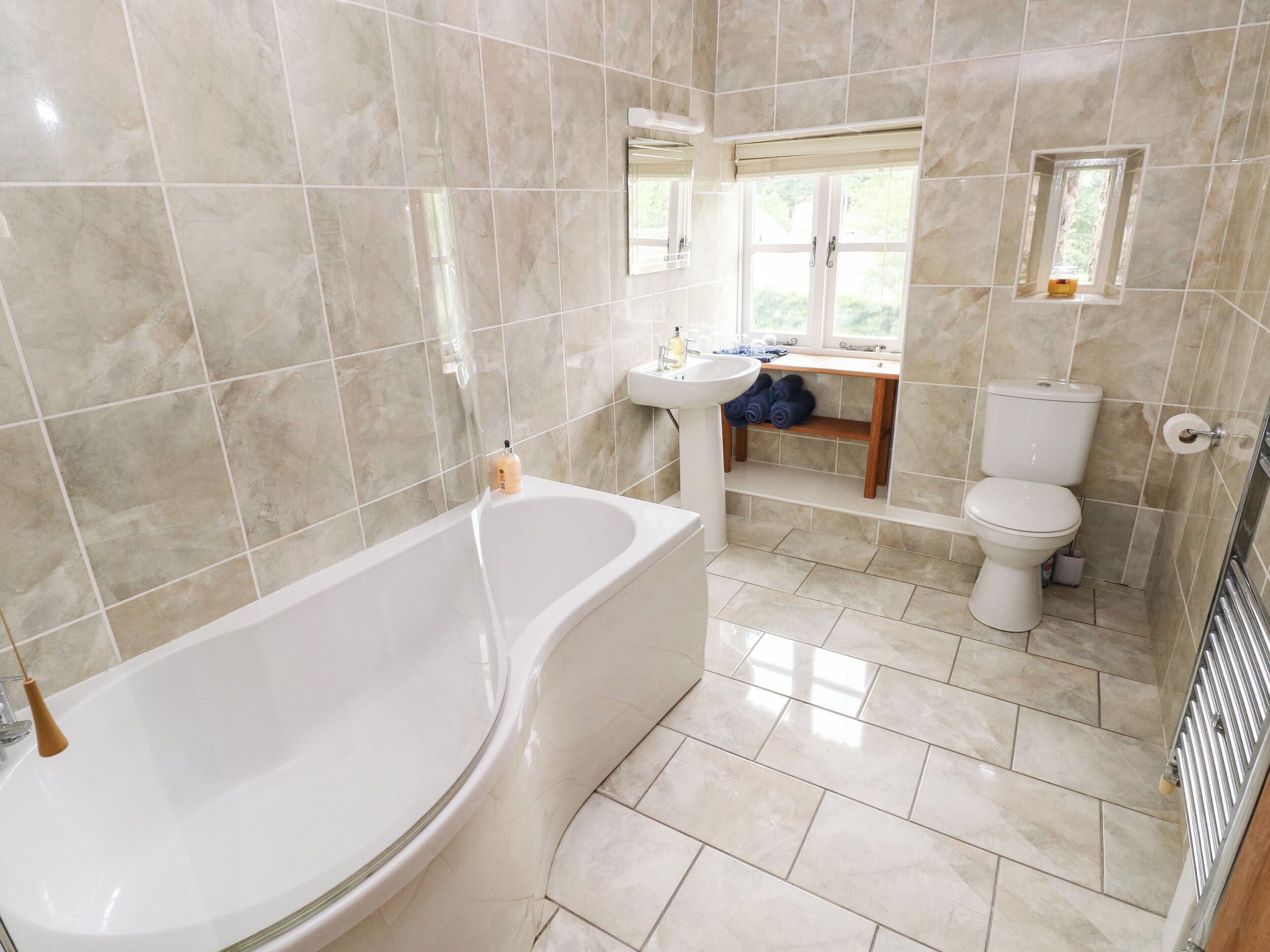A bathroom with a bathtub, sink, toilet, and a window.