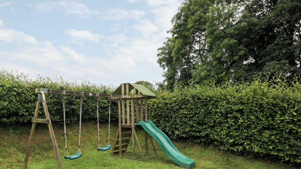 A wooden swing set with a slide in a grassy backyard. - Gwyddno Lodge (Narberth)