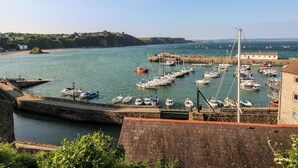 Un port où de nombreux bateaux sont amarrés, un mur de pierre et un bâtiment avec un toit rouge.