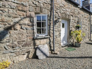 A stone building with a window, a door, and a potted plant. - End Cottage (Newport)
