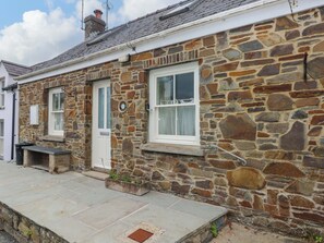 A stone building with two doors, a small porch, and a window with a curtain.