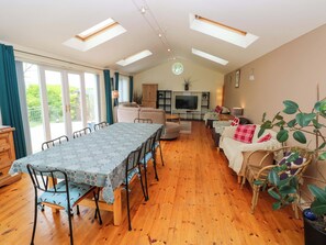 Amplia sala de estar con mesa de comedor, sofás, televisor y balcón con vistas.