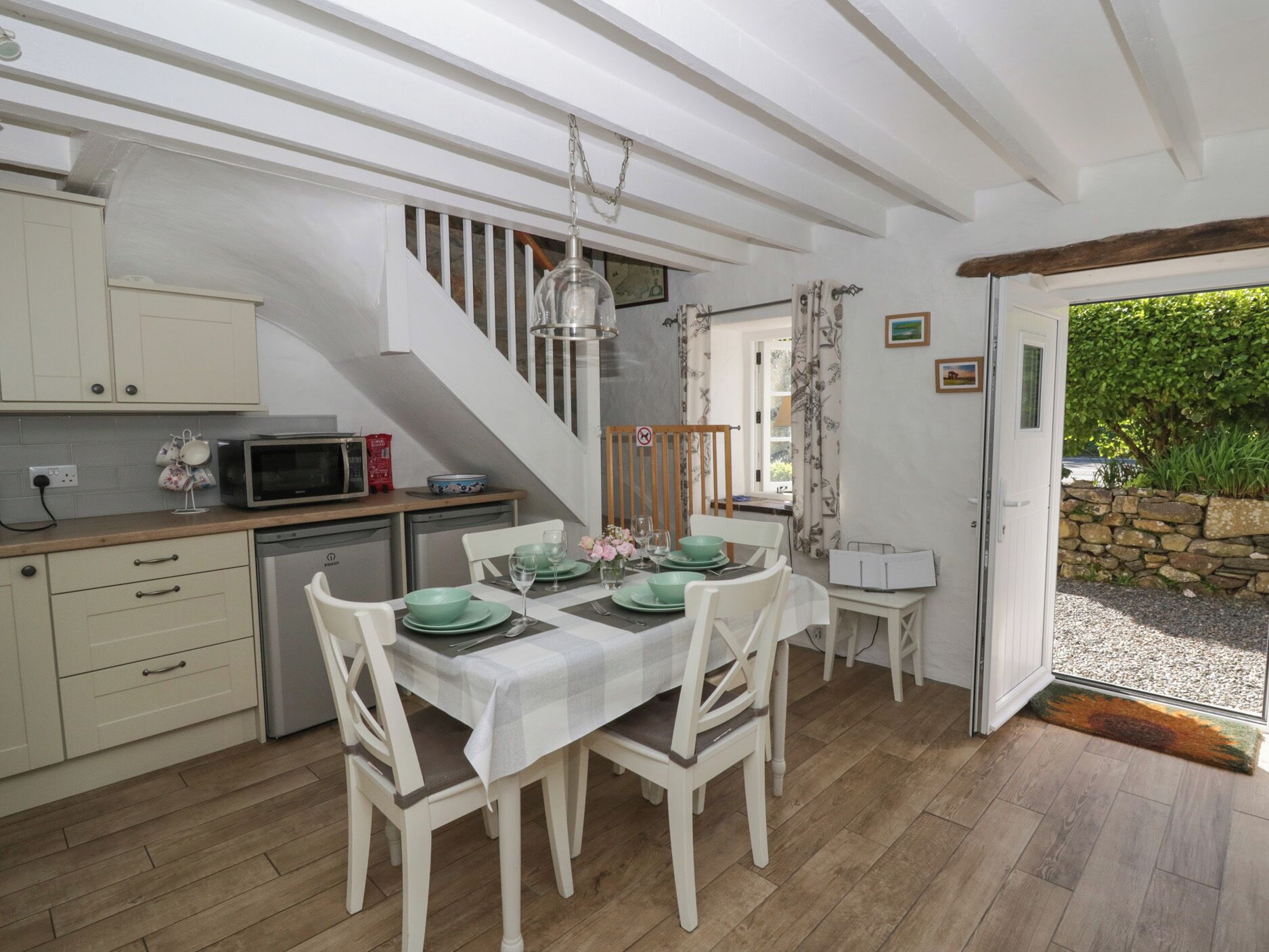 A kitchen with white cabinets, a dining table set with green plates, and a staircase leading to another level.