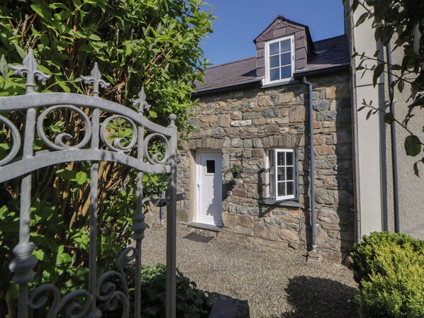 Un bâtiment en pierre, doté d’une petite fenêtre et d’une porte, entouré de verdure.