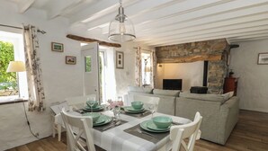 A dining area with a table set for four, a sofa, and a stone fireplace. - Middle Cottage (Newport)