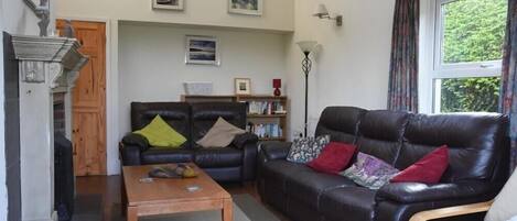 A living room with a fireplace, two sofas, a coffee table, and a bookshelf.