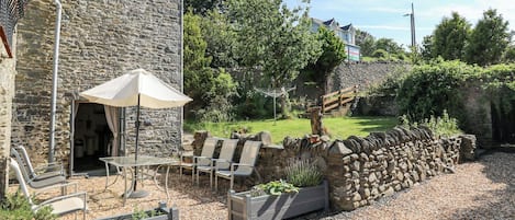 A stone building with a patio area featuring outdoor seating and planters.