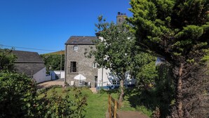 A stone house with a wooden deck and a small garden. - Dewi Villa (Aberaeron)