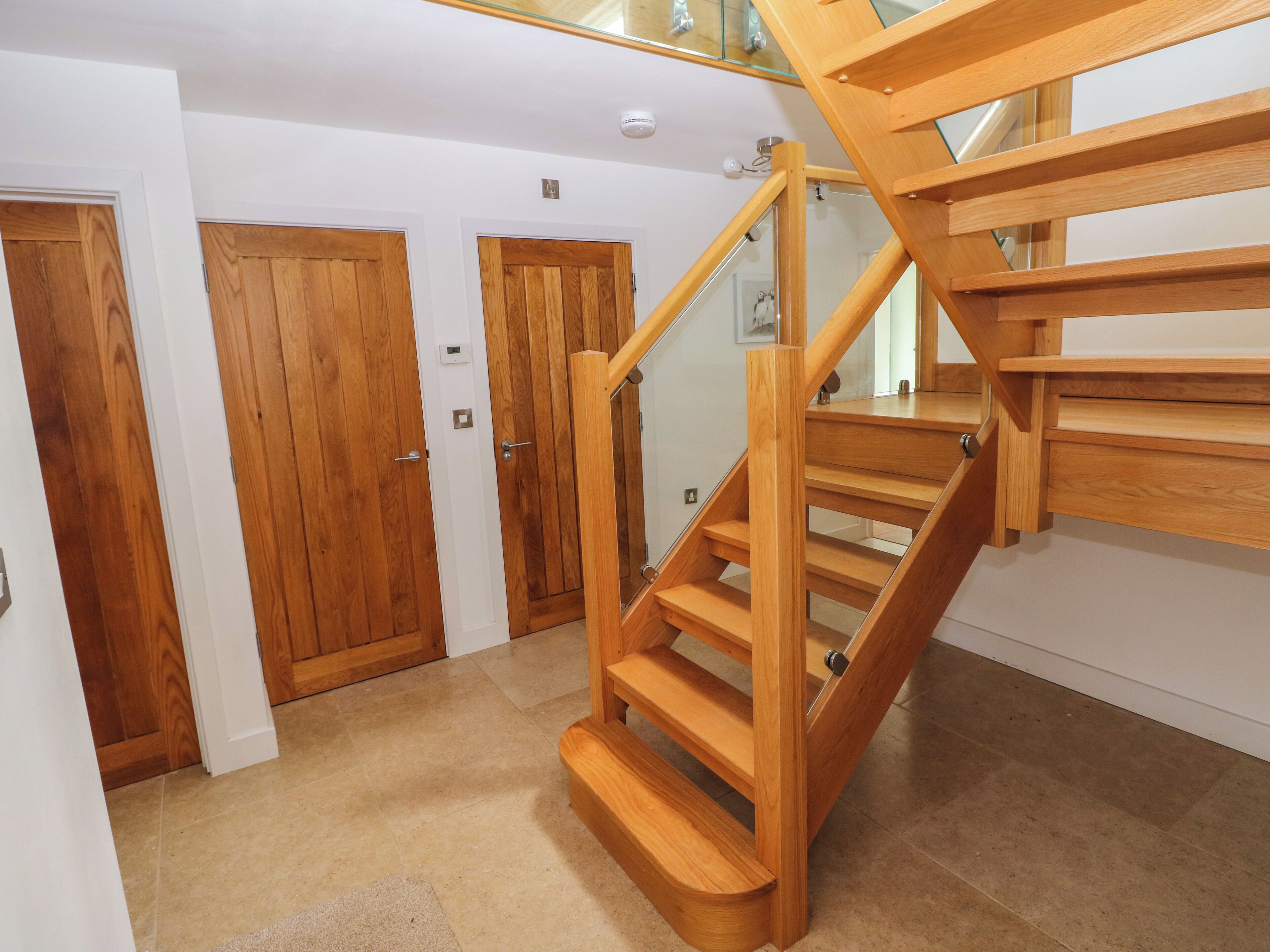 A wooden staircase with glass railings leading to a landing.