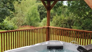 A hot tub on a wooden deck with a view of a lush garden. - Pond Cottage (Llandysul)