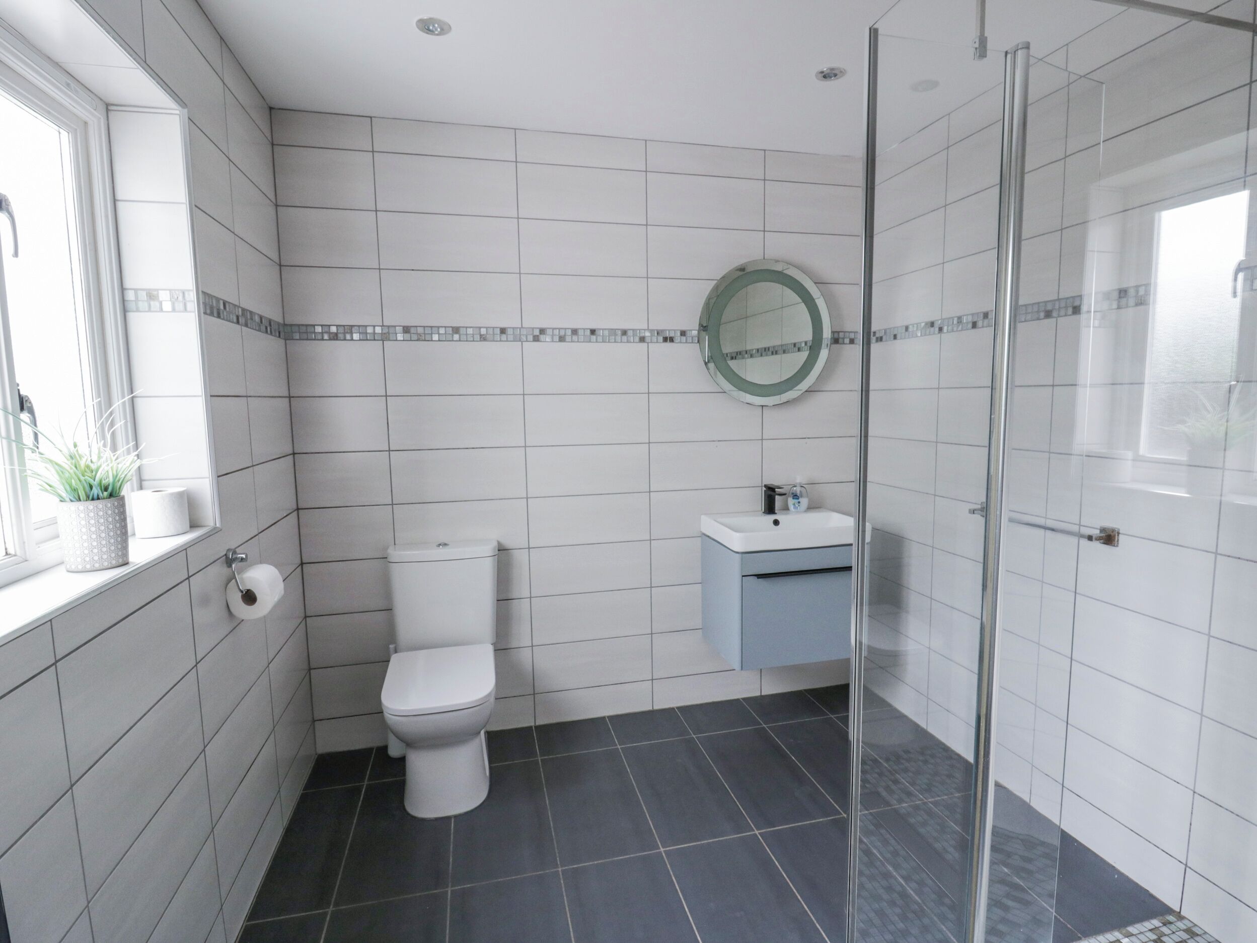 Un baño moderno con inodoro, lavamanos y ducha.