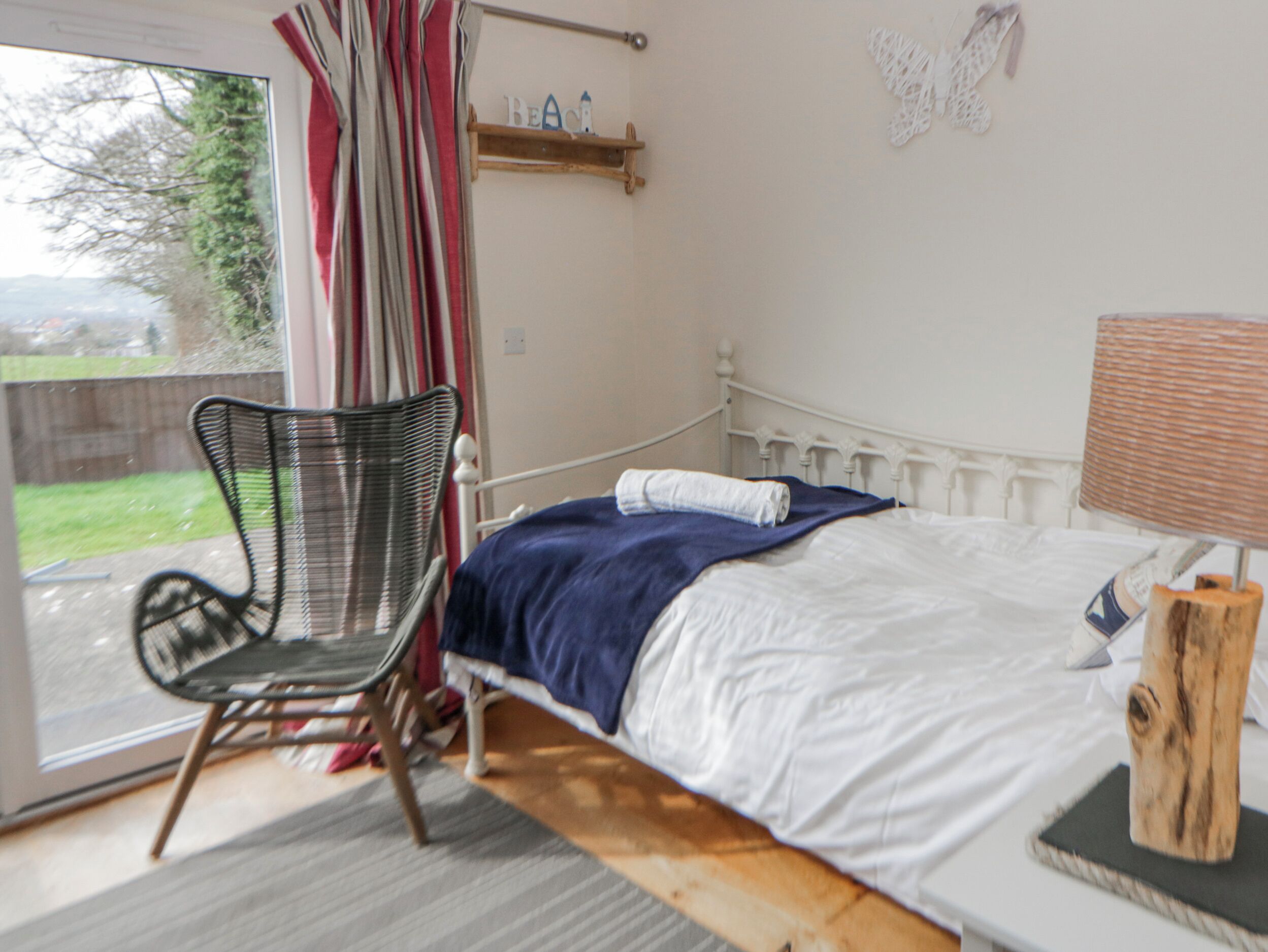 Une chambre à coucher avec un lit, une chaise, une lampe et une vue sur l’extérieur.