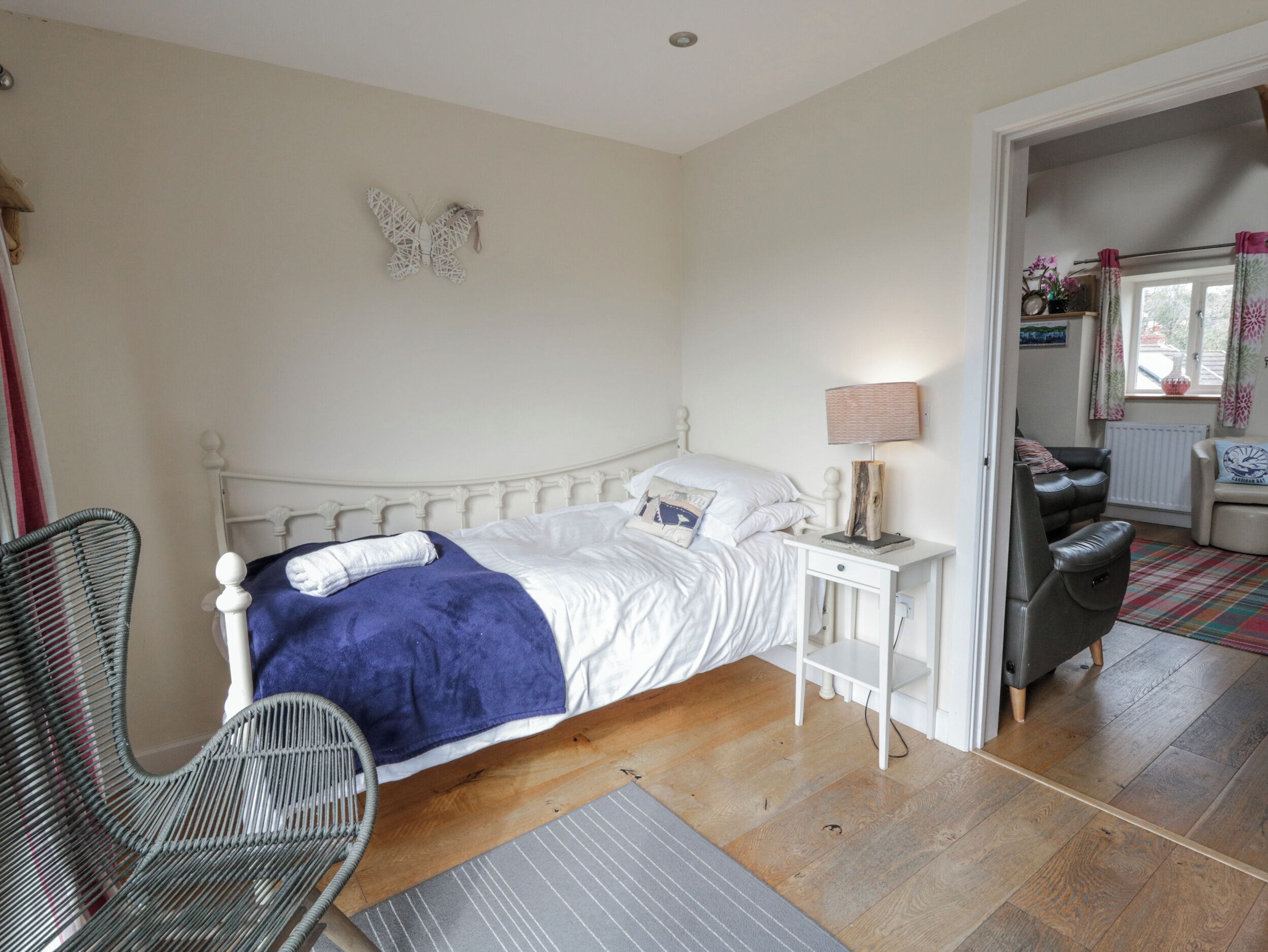 A bedroom with a bed, a chair, a bedside table, and a lamp.