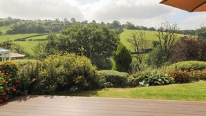 A patio with a view of rolling green hills and trees. - Dan Castell Cottage (Llandeilo)