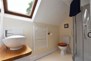 Un baño moderno con tragaluz, lavabo sobre encimera, inodoro y cabina de ducha de cristal.