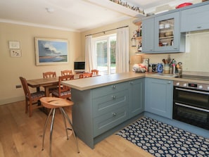A kitchen with a dining area, a TV, and a window with curtains.