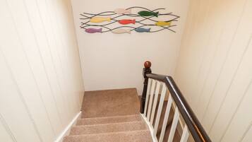 A carpeted staircase with a wooden handrail and a wall-mounted fish decoration.