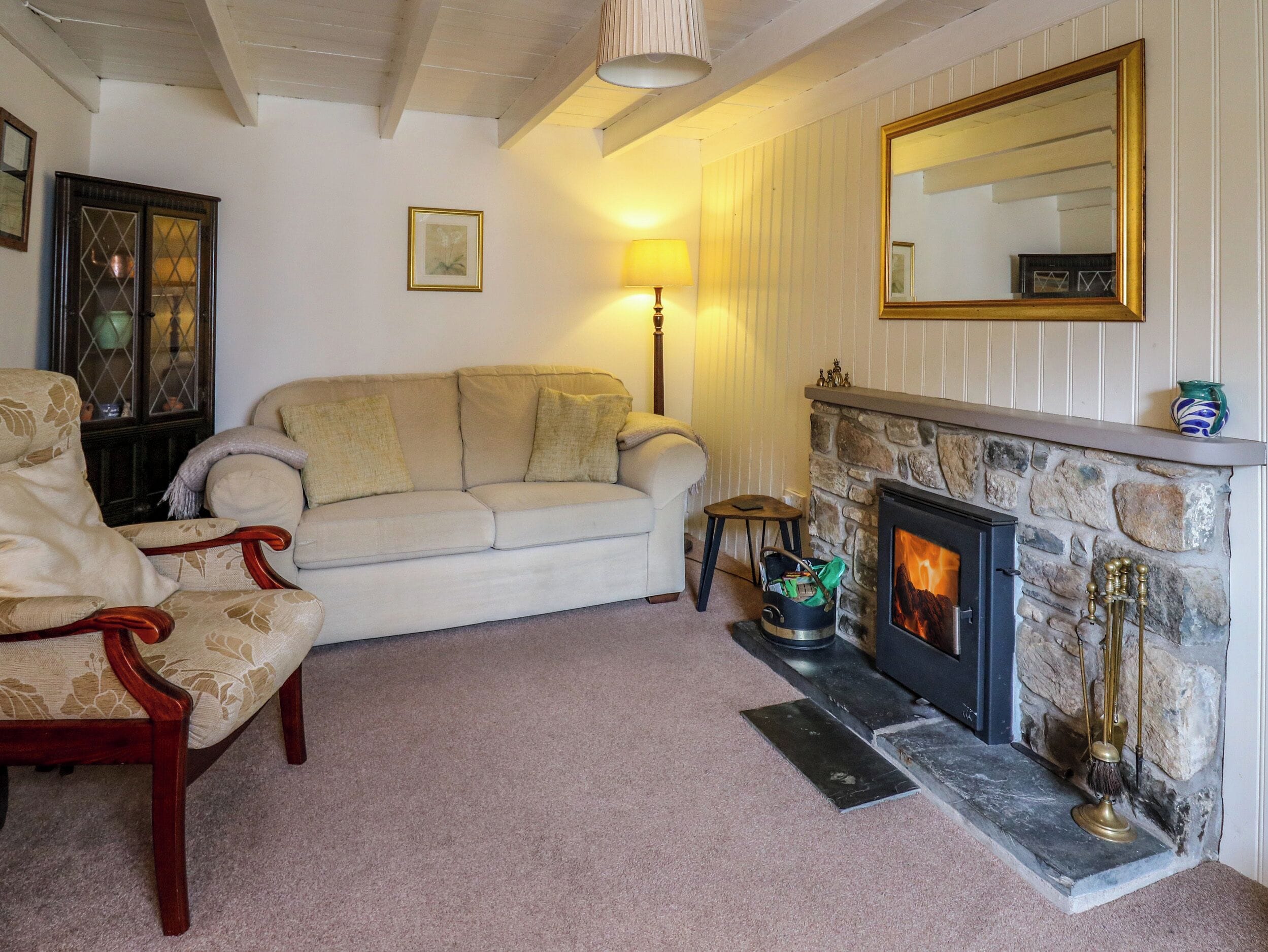 Ein gemütliches Wohnzimmer mit Sofa, Sesseln, Kamin und Spiegel an der Wand.
