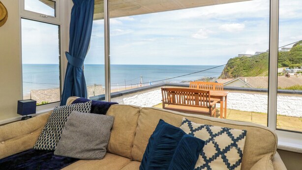 A room with a sofa, a table, and a view of the beach.