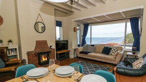A living room with a fireplace, a sofa, a television, and a dining table set for four.