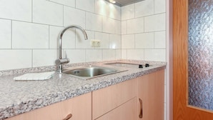 Una cocina con pileta de acero inoxidable, encimera de granito, armarios de madera y campana extractora de acero inoxidable.