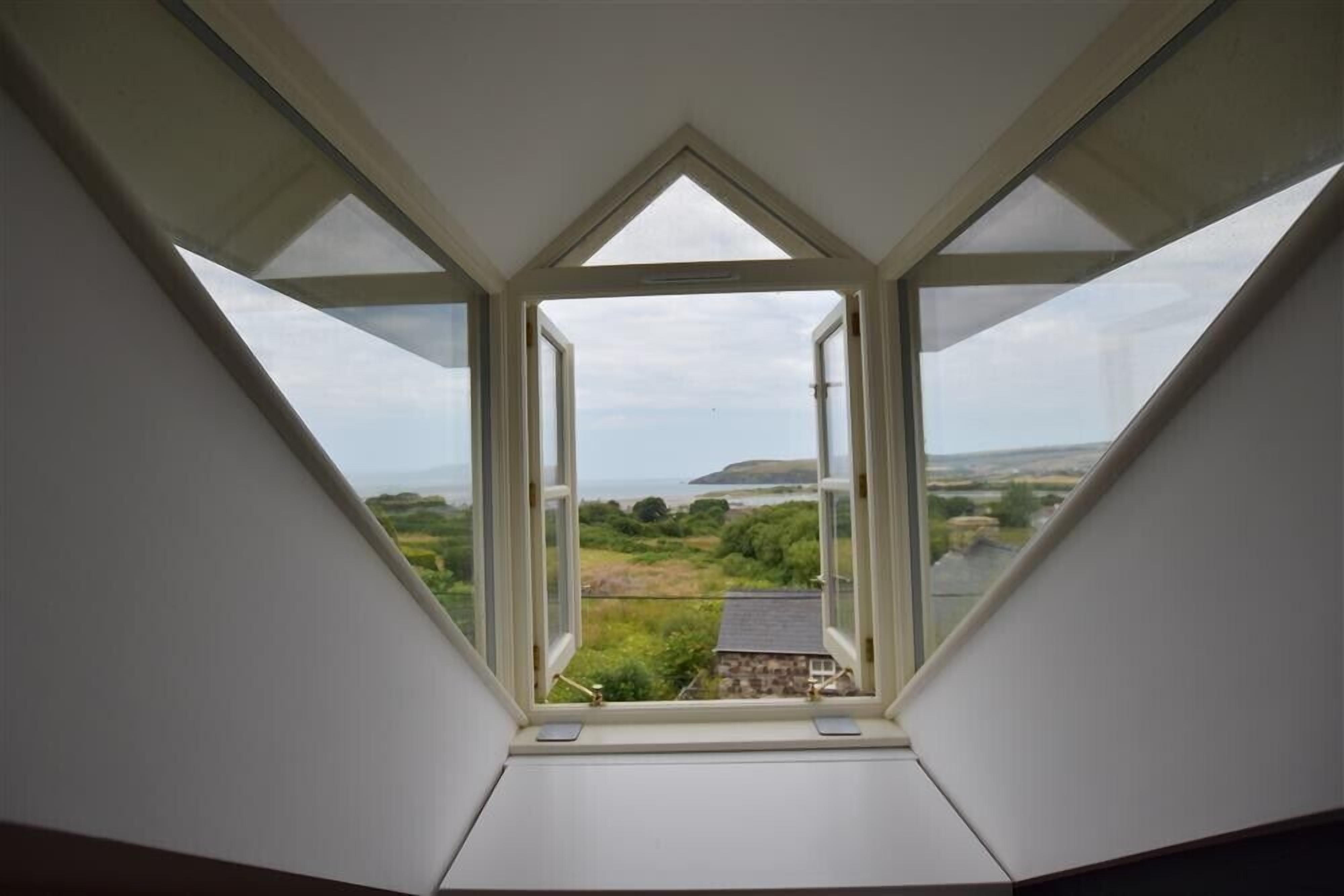 A skylight with a view of a rural landscape, including fields and a distant hill.