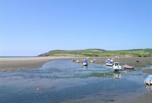 A coastal scene with boats on a sandy beach and calm water. - Gwelfor, Newport (Fishguard)
