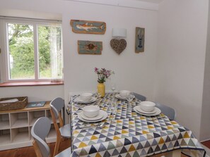A dining area with a table set for four, chairs, a vase with flowers, and wall art.