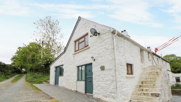 A white building with a stone staircase, a door, and a window. - Little Barn Cottage (Newport)