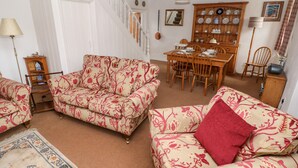 Una sala de estar con sofás estampados, una mesa de comedor y una escalera.