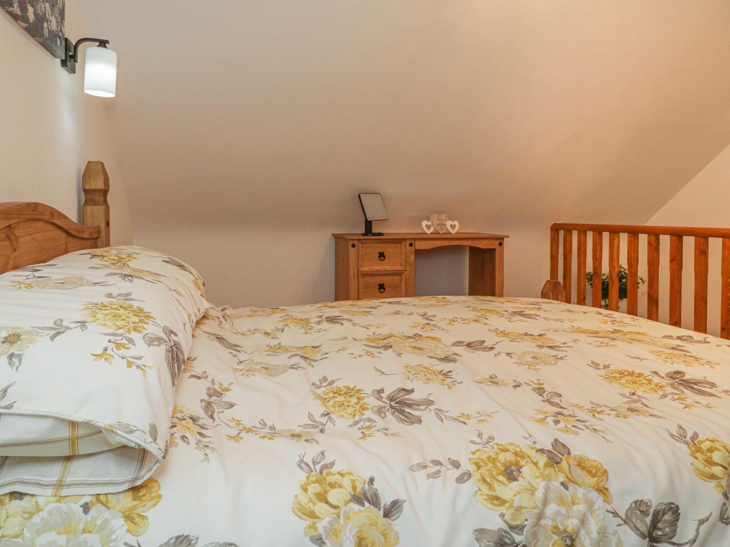 A bedroom with a bed, a wooden desk, and a nightstand.