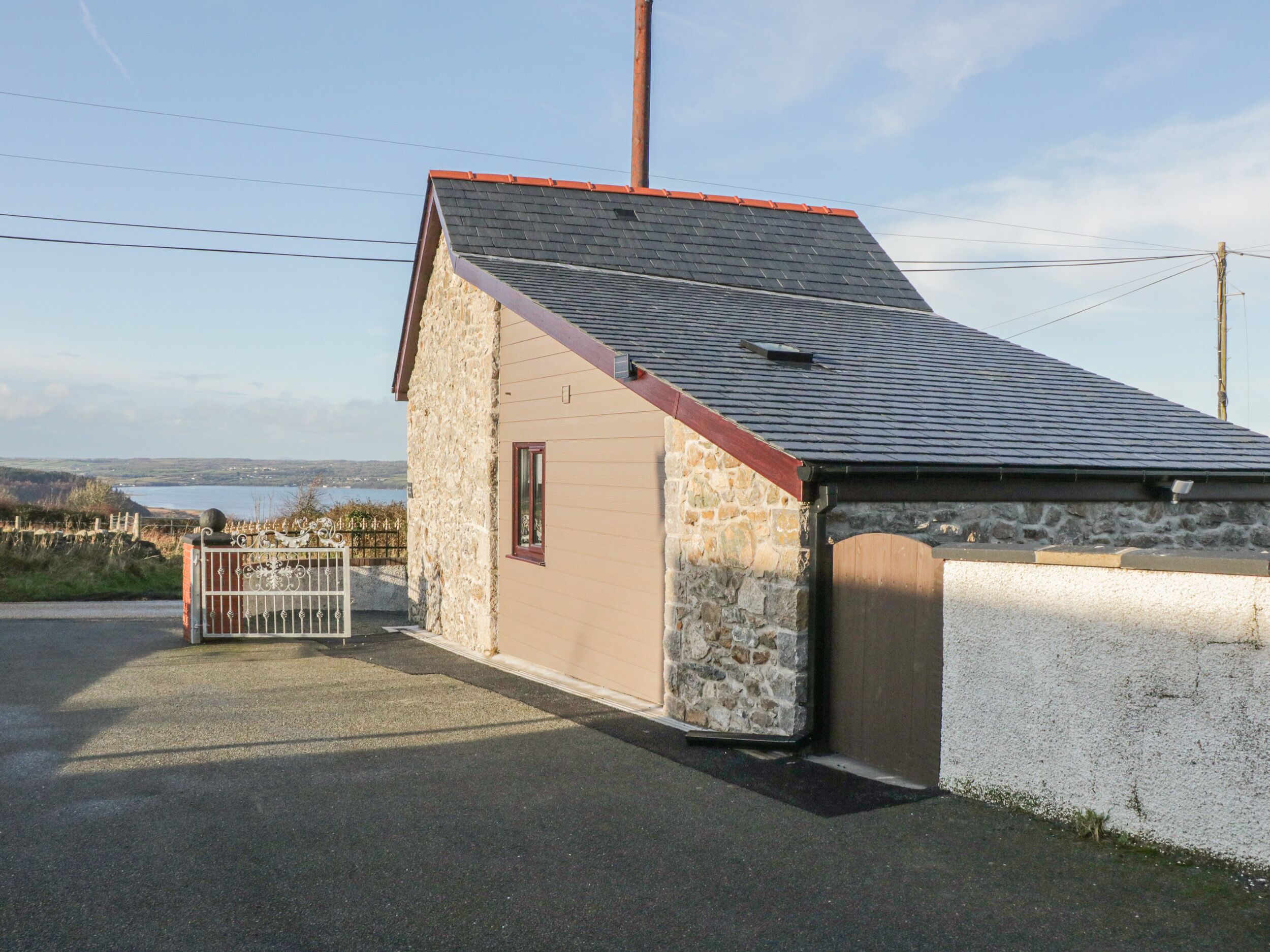 A small stone building with a sloped roof and a metal gate.