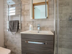 Une salle de bain avec une douche à parois de verre, un meuble-lavabo avec un miroir et un porte-serviettes.