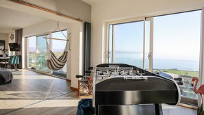 Una habitación amplia con una mesa de fútbol, una hamaca y vista al mar.