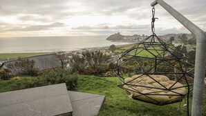 Una silla colgante con vistas a un pueblo costero, el mar y una colina con una construcción que parece un castillo.