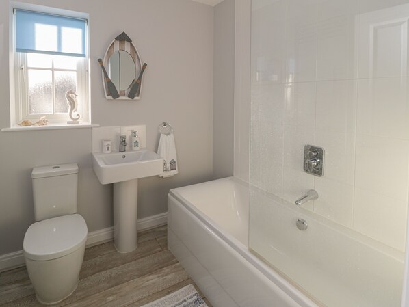 A bathroom with a toilet, sink, and bathtub. - Sandy Corner (Filey)