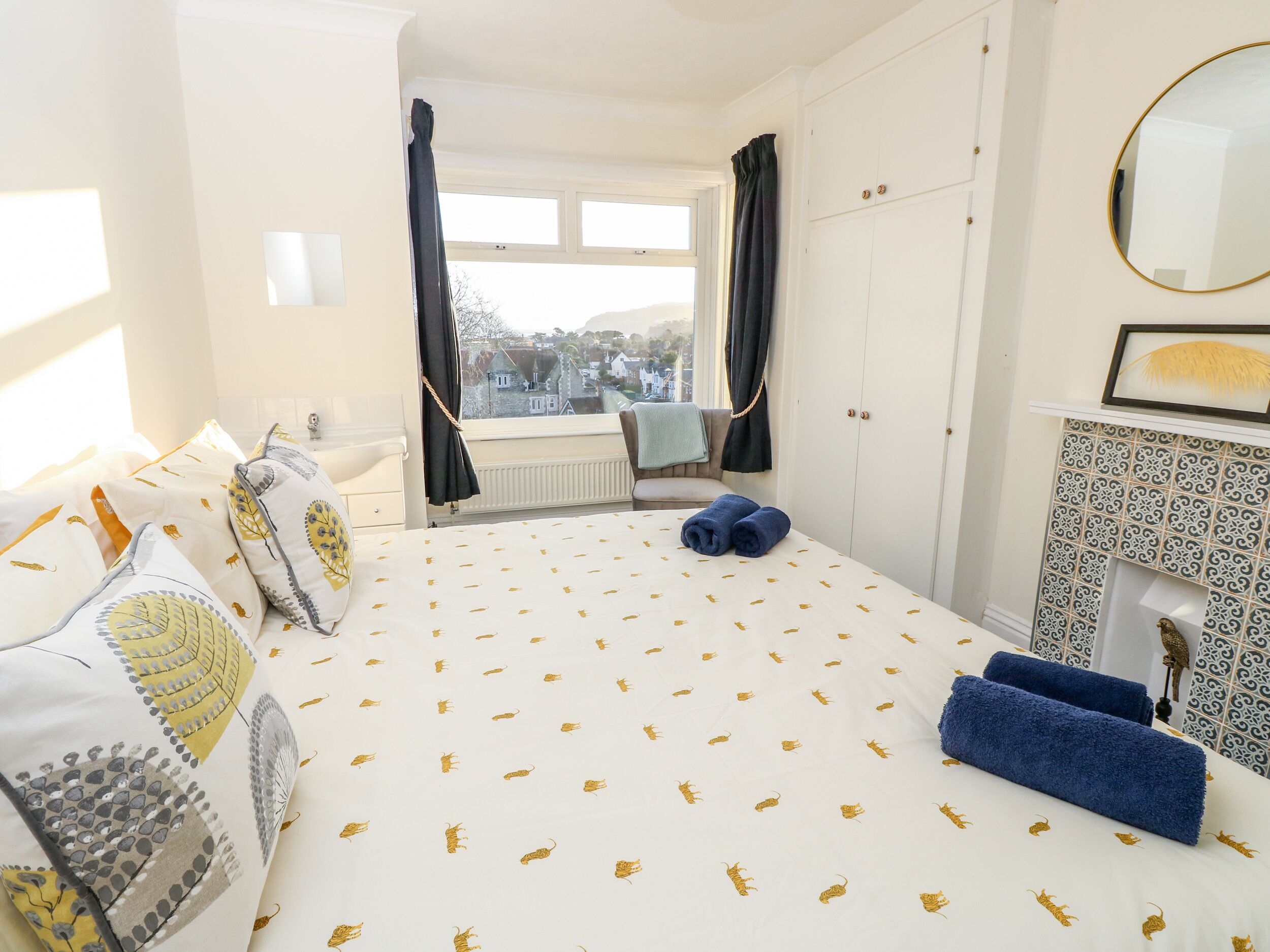 Un dormitorio con cama, cómoda, espejo y vistas al exterior.